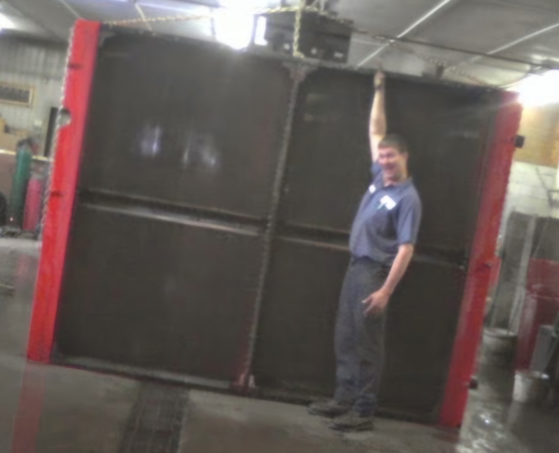 Technician standing beside a massive radiator core for scale
